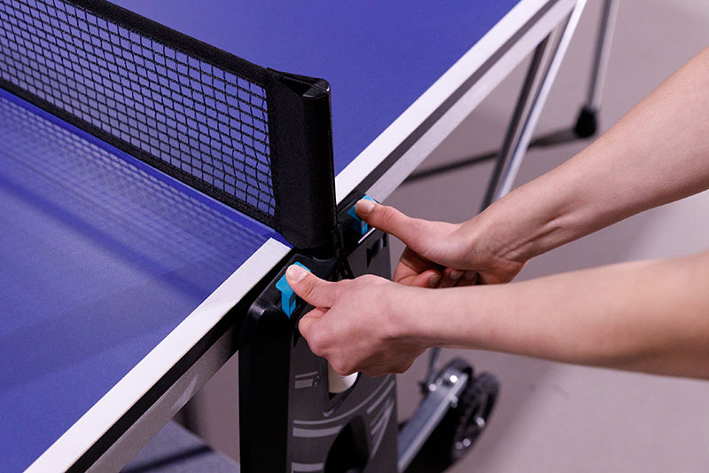 mains entrain de déverrouiller la table de ping pong Cornilleau 100 indoor